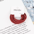 Close-up of deep red high-elasticity hair bands set on a minimalist white card holder - Caramel color