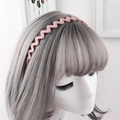 Detail view of a matte pink wavy headband with anti-slip teeth on a model's head - Pink