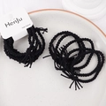 Close-up of black braided elastic hair bands with fine texture on a white tray - Cable Black