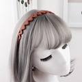 Detail of red matte wave headband with anti-slip teeth shown on model for daily hair styling - Orange