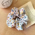 Gros plan d'un chouchou à fleurs sur un bureau vintage avec une tasse de café - Style B - Blanc