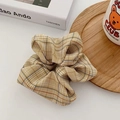 Detail of yellow houndstooth fabric scrunchie with soft pleats on a cozy wooden tray - Turmeric
