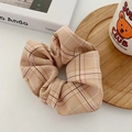 Close-up of brown houndstooth fabric scrunchie on a wooden tray for hair styling - Khaki