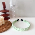 Close-up of mint green pleated fabric headband with protective black rubber ends - Light Green