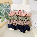 Close-up of four colorful satin scrunchies in pink, green, and navy on a display card - Pink Green Navy