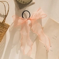 Detailed shot of soft pink organza bow hair tie with long ribbons and black elastic band - Pink
