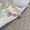 Close-up of vintage purple crystal hair clip with small white zircons on golden metal base - Rhinestone Style - Purple