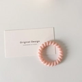 Close-up of a pale pink spiral telephone wire hair tie on a white display card - Light Pink