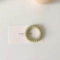 Detailed macro view of a light green spiral telephone wire hair tie on a white card - Light Green