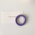 Close-up of taro purple spiral hair tie with glossy finish on original design card - Purple