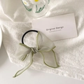 Détail d'un chouchou en organza vert clair avec des bords cousus délicats - Vert