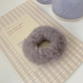 Detail of plush faux fur hair tie in dusty purple on a plaid notebook background - Gray