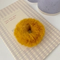 Macro shot of fluffy bright yellow faux fur scrunchie on a checkered notepad - Turmeric
