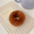 Detail shot of a soft caramel brown plush scrunchie on a cozy home desk setup - Caramel color