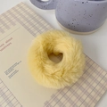 Detailed texture of a bright yellow plush hair scrunchie on a beige notebook - Milk Yellow