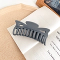 Detail view of large matte dark grey hair claw clip showing wavy teeth and metal spring - Gray