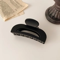 Primer plano de una pinza para el pelo negra mate con diseño curvo minimalista y hueco - Negro