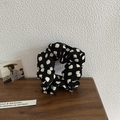 Gros plan d'un chouchou noir à pois blancs posé sur un support en bois de style rustique - Noir à Pois