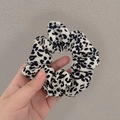 Gros plan d'un chouchou léopard élégant avec texture de tissu doux et plis élastiques - Motif Vache Blanc