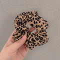 Close-up of a leopard print scrunchie made of elastic fabric held in hand - Cow Coffee