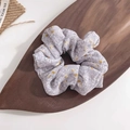 Detailed macro view of a light purple floral chiffon scrunchie on a wooden tray - Taro Purple
