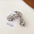 Detail of large acetate hair claw with elegant marble texture on a white display card - Gray