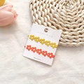 Dettaglio di fermagli per capelli floreali color caramella gialli e arancioni su carta - Set Fiori Giallo