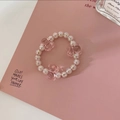 Close-up of pink crystal beads and cute teddy bear charms on a stylish hair tie bracelet - Pink