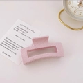 Close-up of a pink matte rectangle hair claw clip with speckled texture on a desk - Speckled Pink