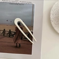 Primer plano de una horquilla en forma de U crema sobre un fondo de revista de moda - Blanco Leche