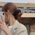 Chouchou noir à motifs blancs porté sur un chignon pour un style élégant français - Noir