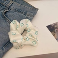 Close-up of dual-tone scrunchie with blue smiley faces on cream satin fabric surface - Mint Green Smile Face