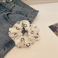 Detail of a white satin scrunchie with smiley face print on denim jeans surface - White Smiley Face