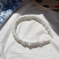 Detailed view of white pleated satin headband with protective anti-slip ends for comfort - White