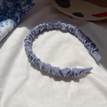 Detail view of the elegant light blue ruched satin headband with soft silk texture - Fog Blue