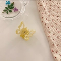 Detailaufnahme einer gelben Haarklammer in Schmetterlingsform mit Perlmutt-Effekt - Mischgelb