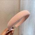 Detail eines hellrosa gerippten Stirnbands mit handgefertigtem Etikett und Textur - Creme-Rosa