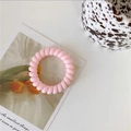 Detail shot of a slim pink spiral telephone cord hair tie on a decorative tulip card - Jelly Pink