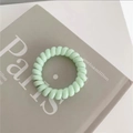 Detail of mint green spiral telephone wire hair tie on a minimalist background - Jelly Green
