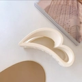 Detail view of a matte cream heart-shaped hair claw clip on a minimalist aesthetic background - Off White