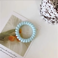 Close-up of light blue spiral telephone wire hair tie on a minimalist artistic desk - Jelly Light Blue