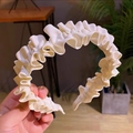 Detail shot of ivory pleated fabric headband with ruffled edges and ribbed texture - Off White