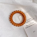 Vista dettagliata di un elastico per capelli a spirale opaco ambra su lino minimalista - Rosso Arancio