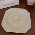 Dettaglio di una piccola clip per capelli color crema su un vassoio di ceramica bianca - Bianco Latte