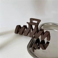 Detailed close-up of a matte dark brown large hair claw clip on a sleek metal tray - Dark Coffee Wave Hair Claw