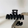 Close-up of a matte black wavy hair claw clip on a sleek silver stainless steel tray - Black Wave Hair Claw