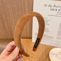 Detalle de una diadema de gamuza marrón con etiqueta artesanal en una bandeja - Camel