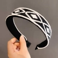 Detail eines gestrickten Haarreifens mit schwarz-weißem Rautenmuster in der Handansicht - Schwarz Weiß Raute