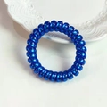 Detailopname van felblauwe spiraal haarelastiek met metallic afwerking op keramiek bord - Helder Metallic Blauw