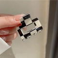 Detail of a small black and white checkered acetate hair claw clip held by hand - Black and White Checkerboard